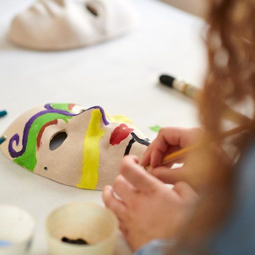 Jugendliche bemalt eine Maske