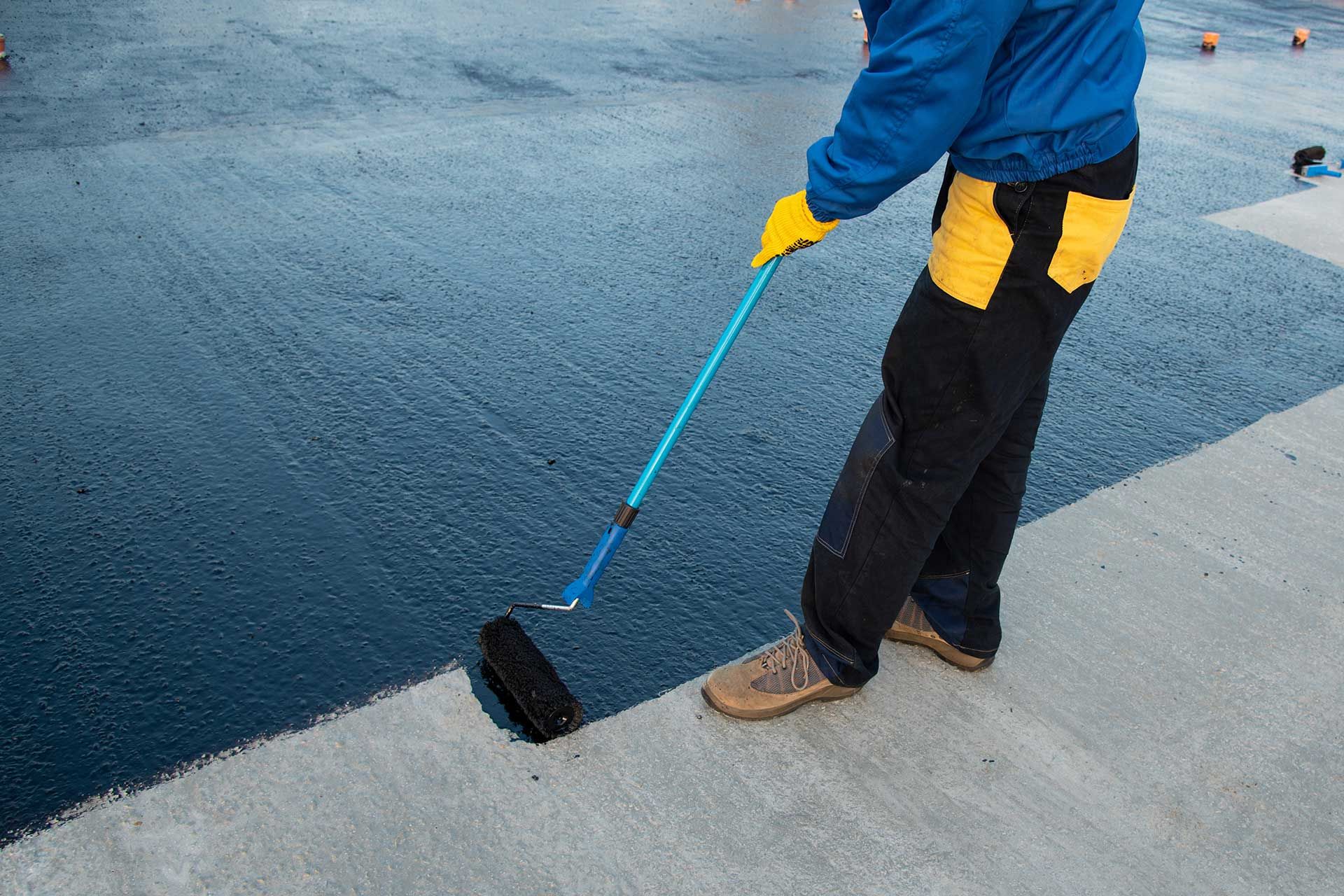 Worker applies bitumen mastic on the foundation