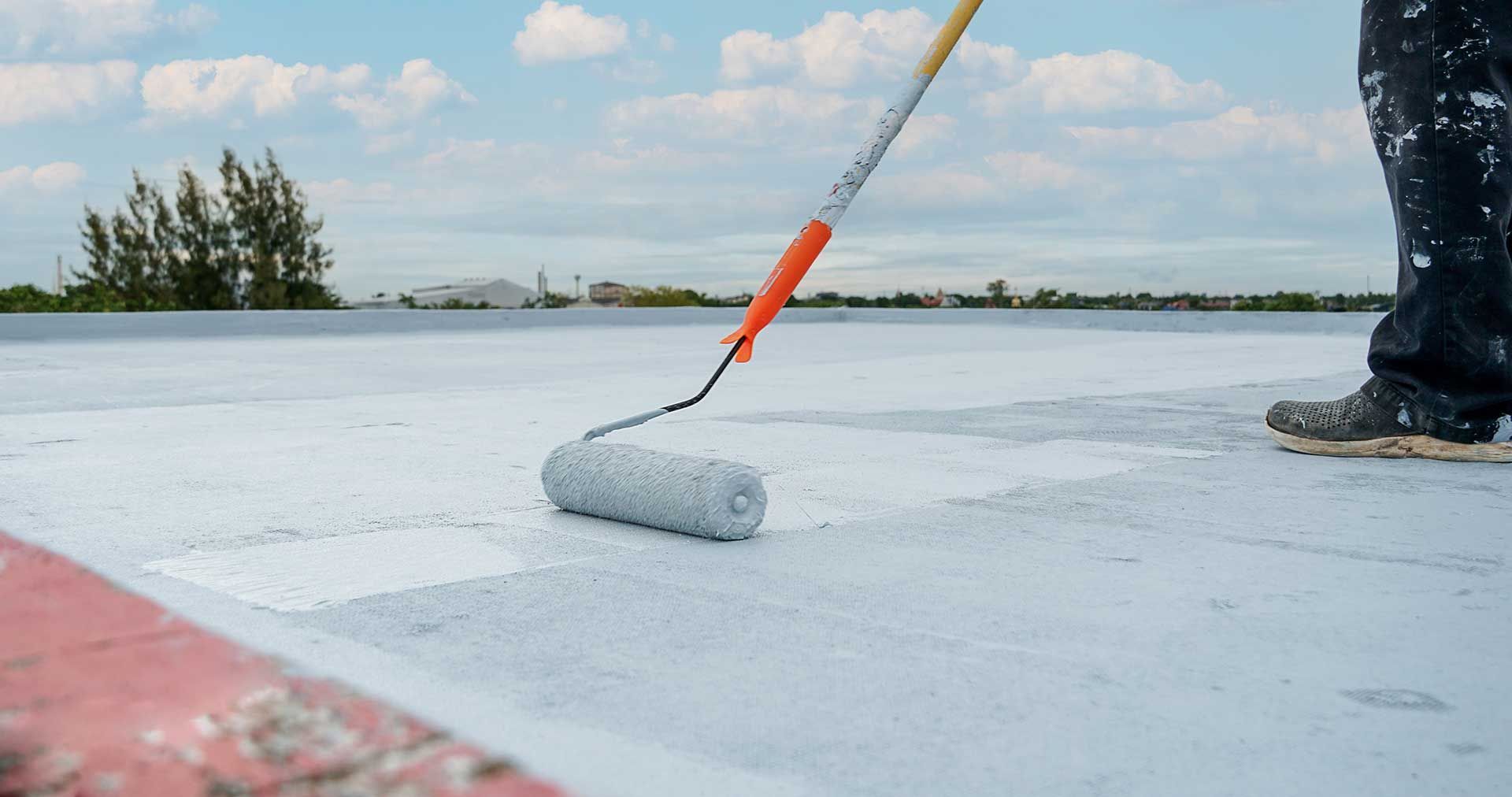 Roofer adding coating to flat roof with roller
