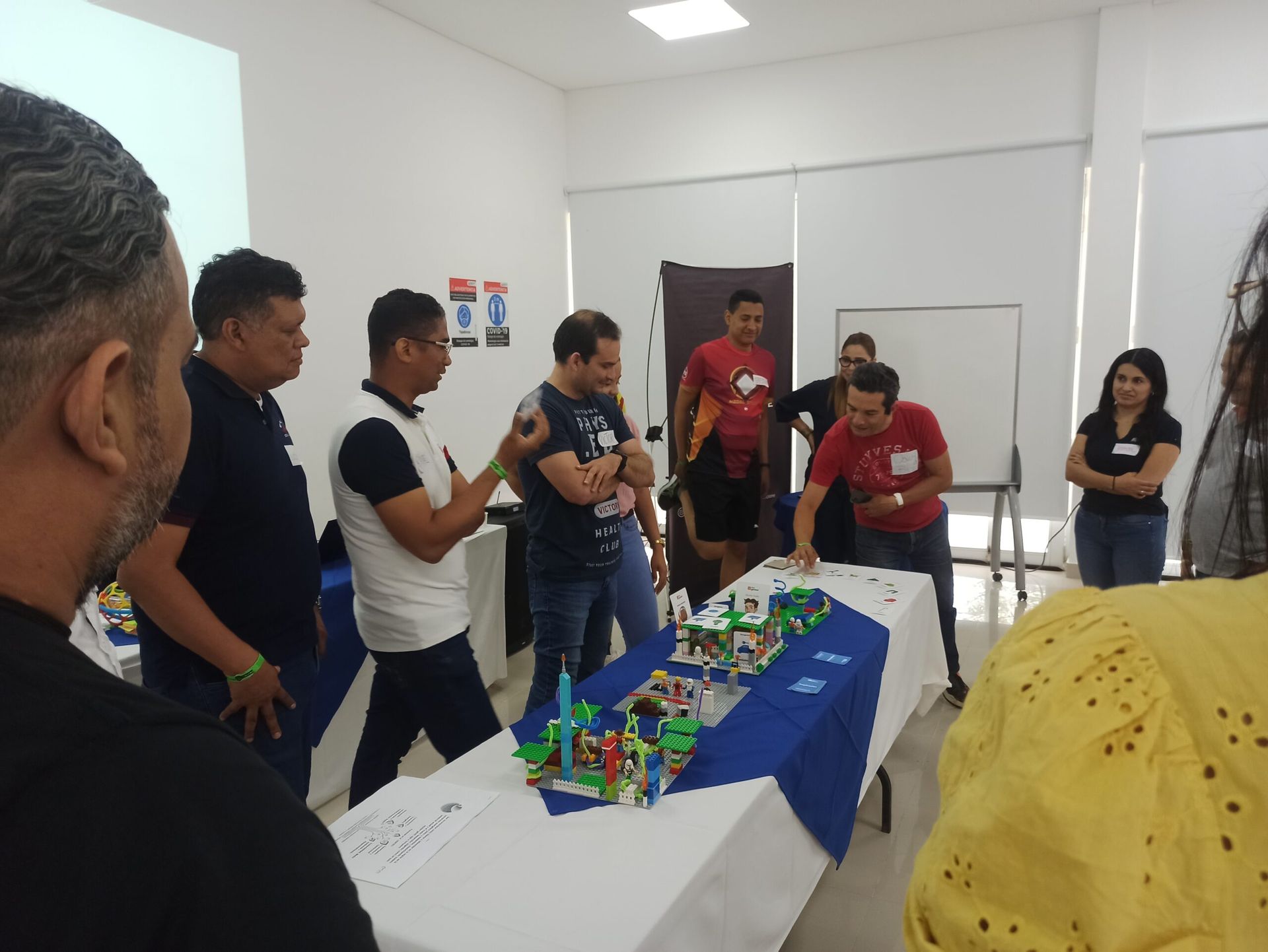 Un grupo de personas está de pie alrededor de una mesa con bloques de Lego encima.
