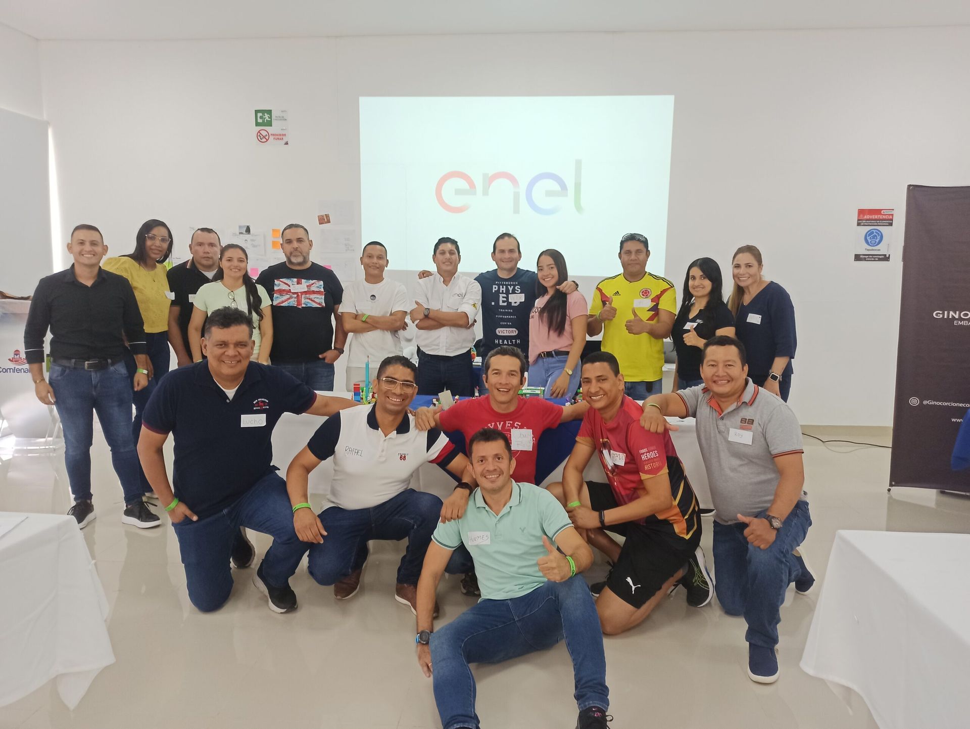 Un grupo de personas posa para una fotografía frente a una pantalla de proyector que dice enel.