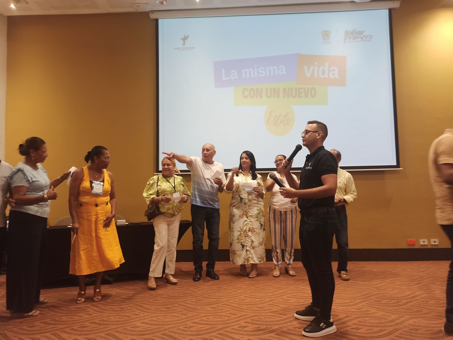 Un grupo de personas está de pie frente a una pantalla grande.