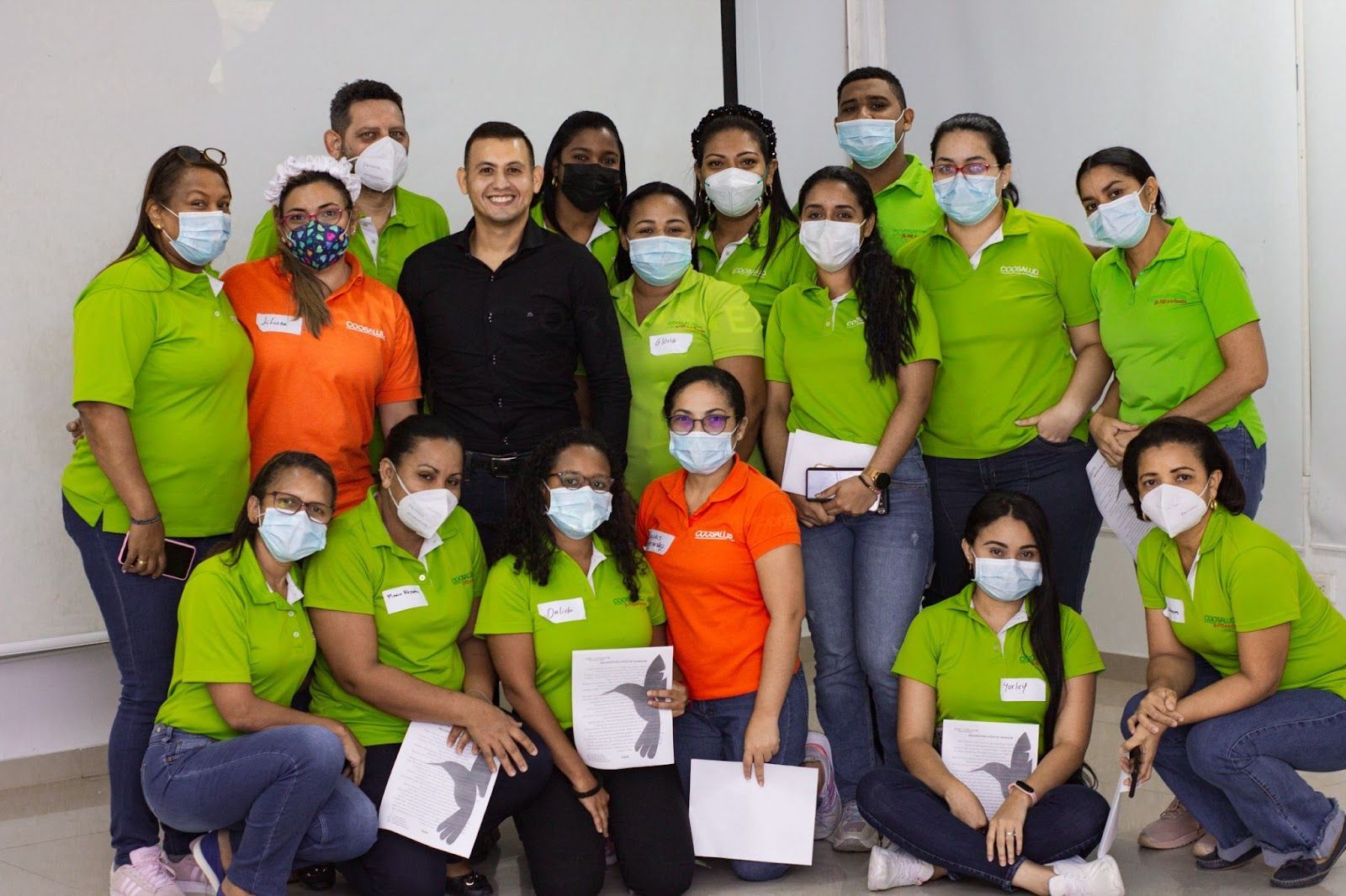 Un grupo de personas con máscaras y camisetas verdes posan para una fotografía.
