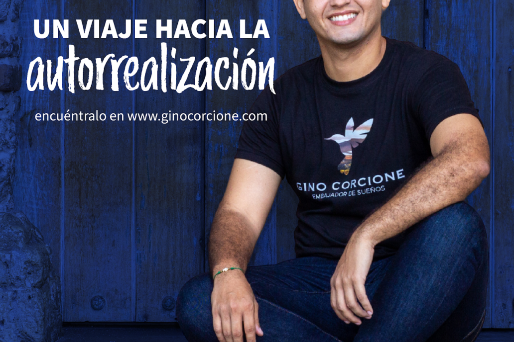Un hombre con una camisa negra está sentado frente a una pared azul.
