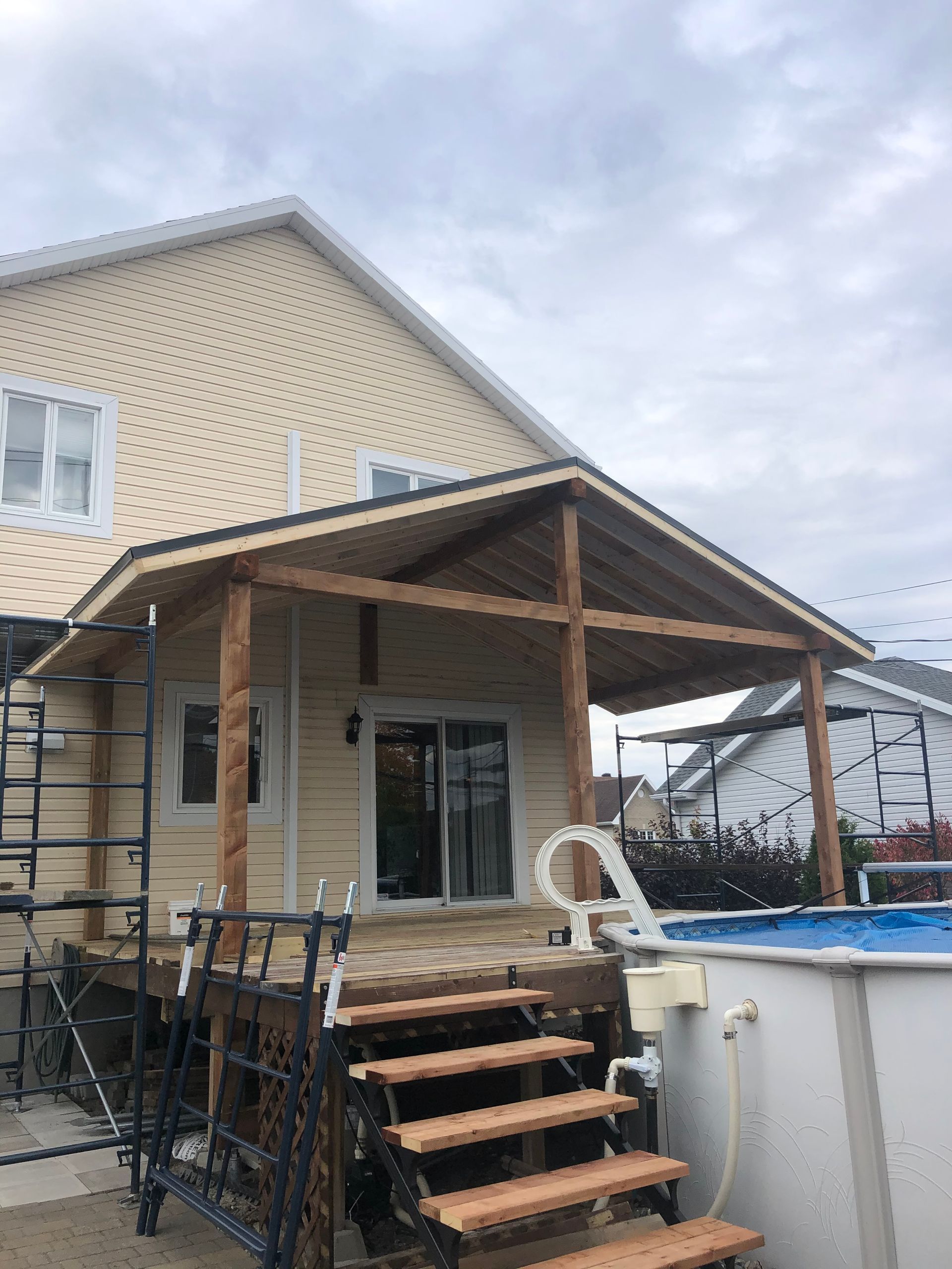 Une maison avec un porche et des escaliers à côté d'une piscine.