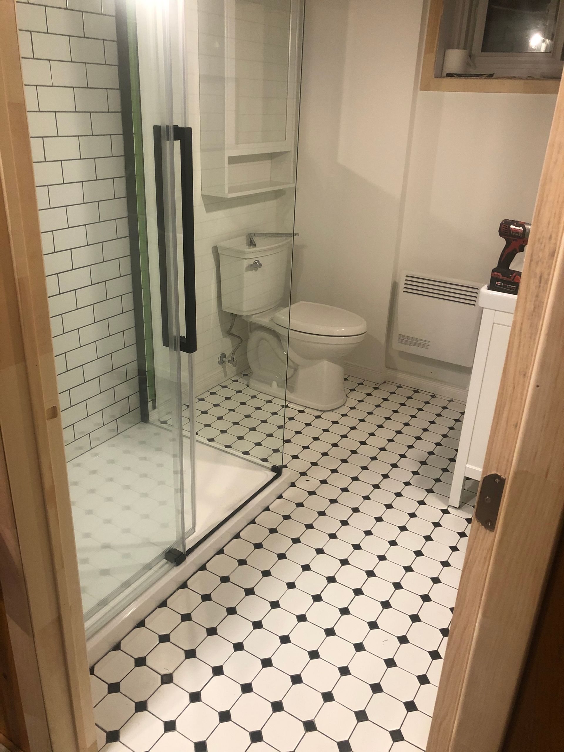 Une salle de bain avec WC, douche et carrelage noir et blanc