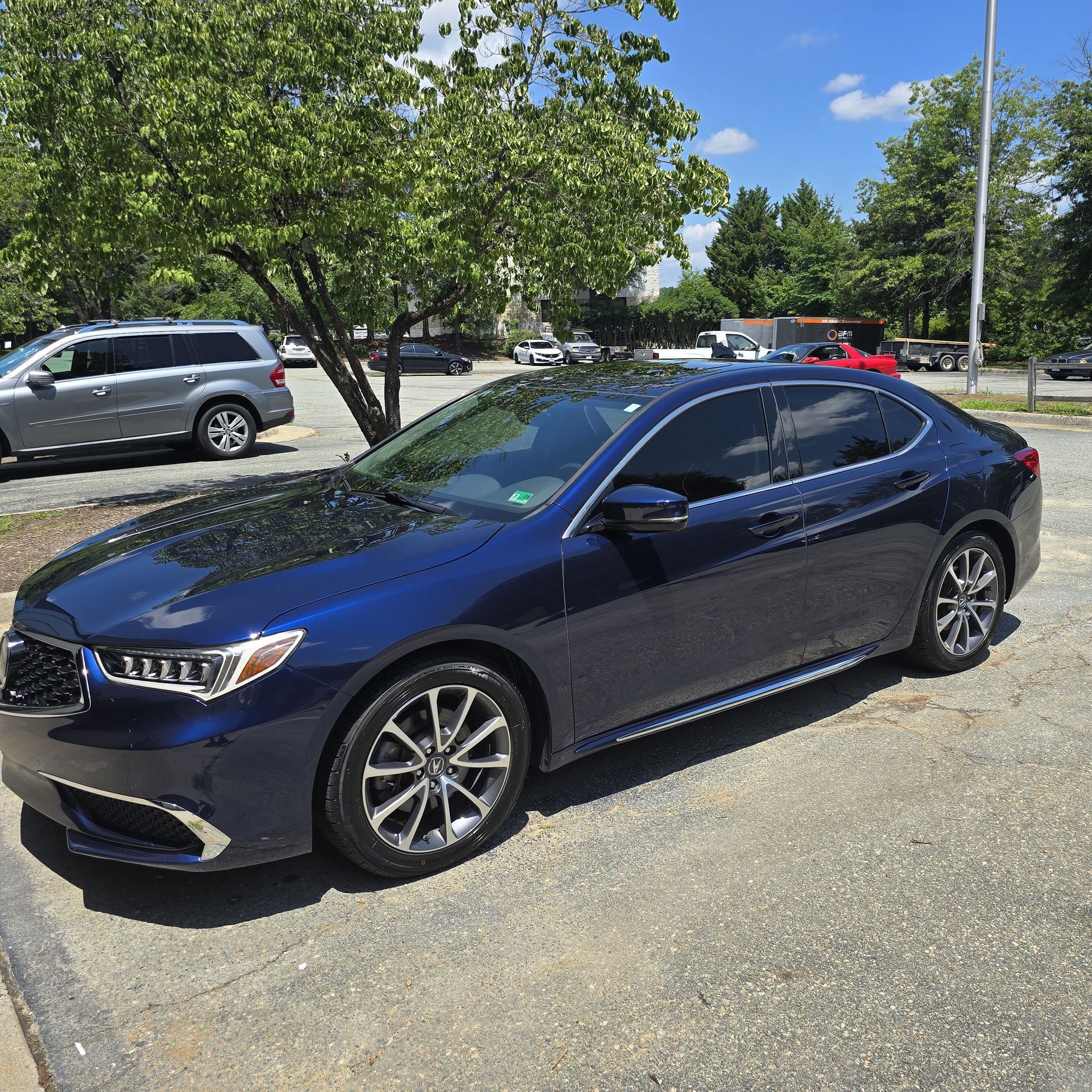 Blue Acura car parked outside on a sunny day.