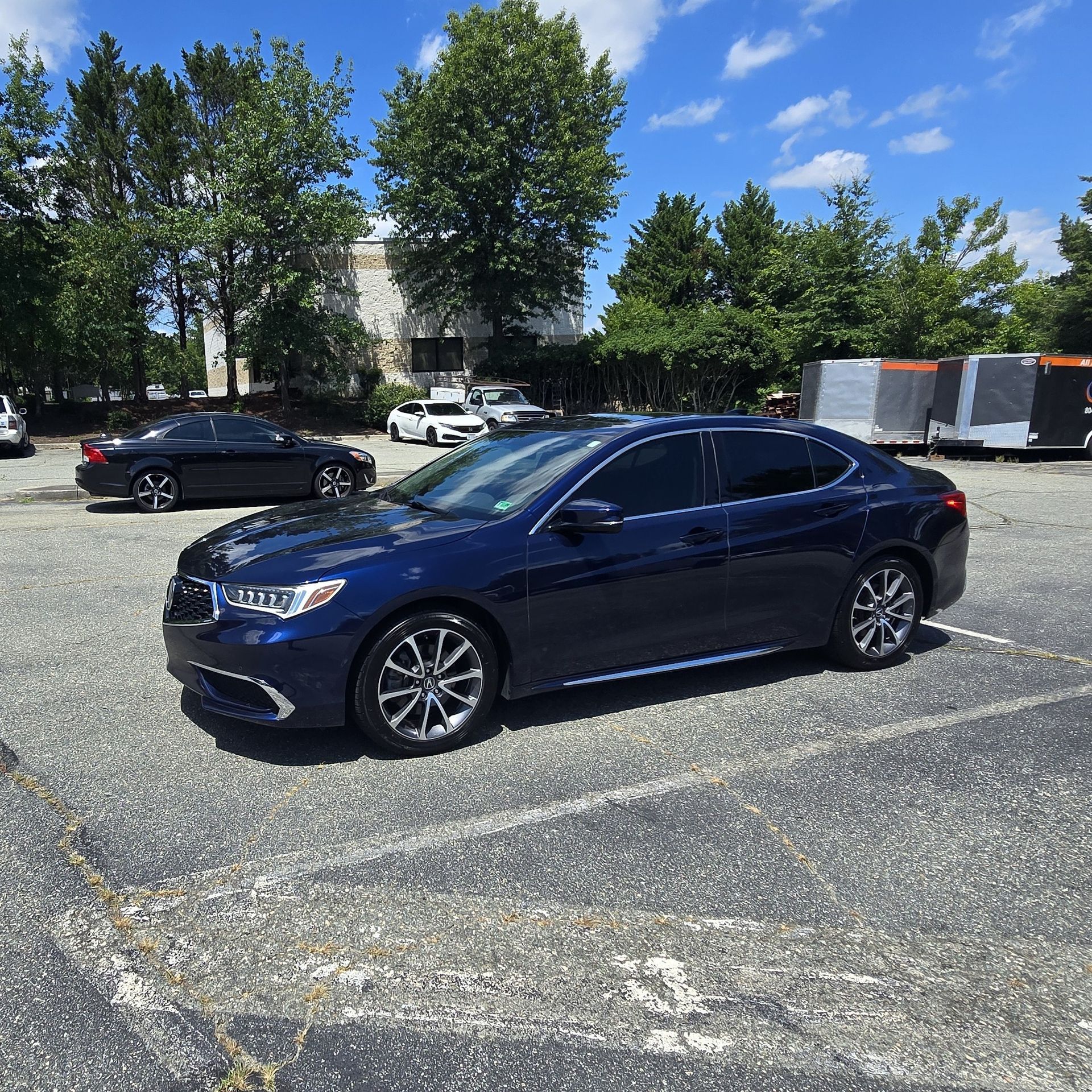 Blue Acura sedan parked outside a building with a blue awning.