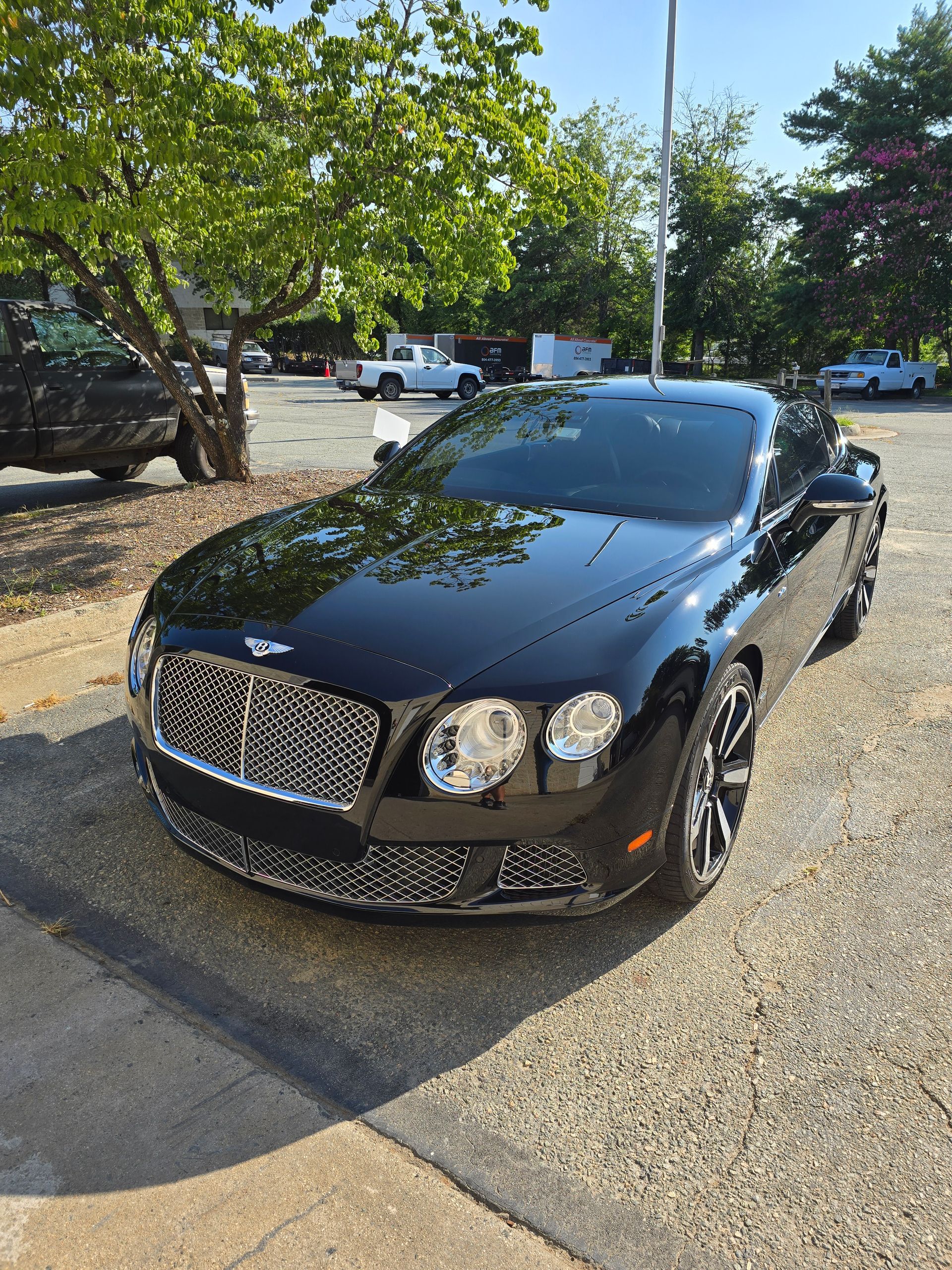 Black Bentley coupe parked outside on a sunny day.