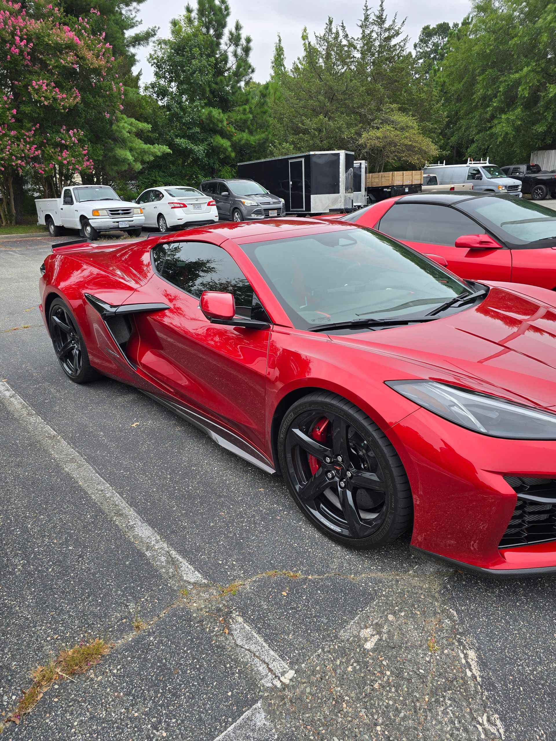 Red Chevrolet Corvette parked in a lot, other vehicles in the background.