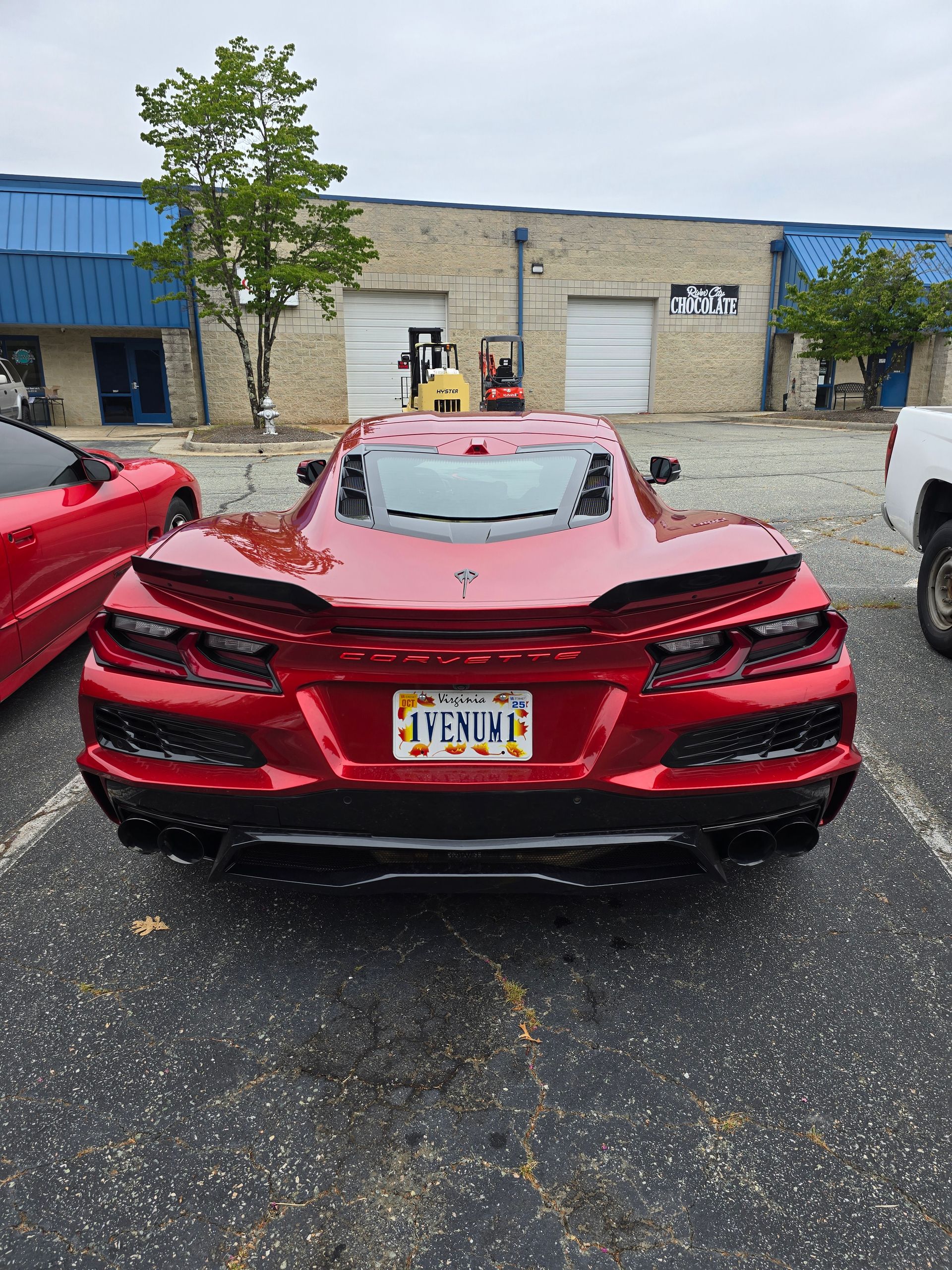 Red Corvette parked in a lot, other vehicles in background.