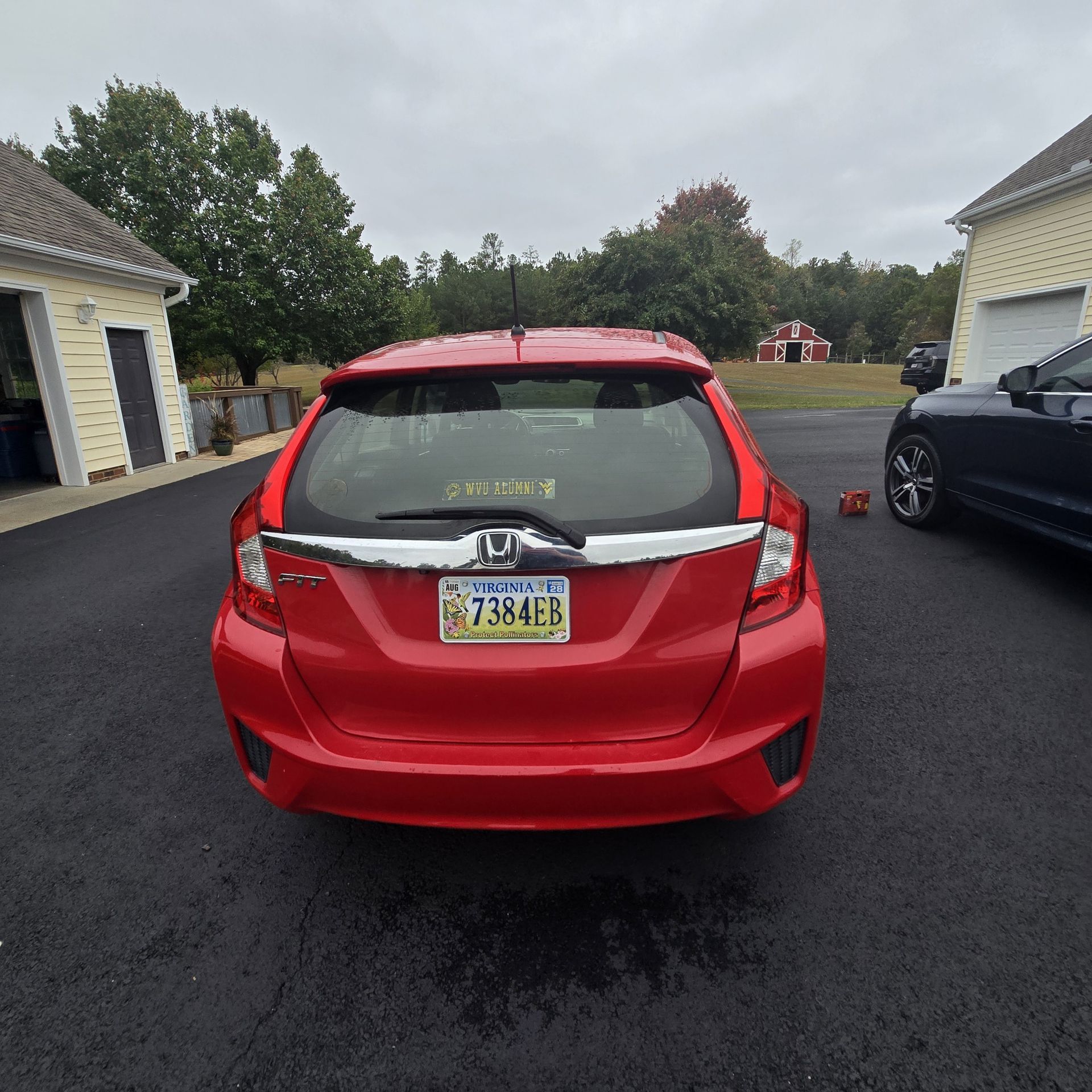 Red Honda Fit hatchback car with Pennsylvania license plate parked on asphalt driveway.