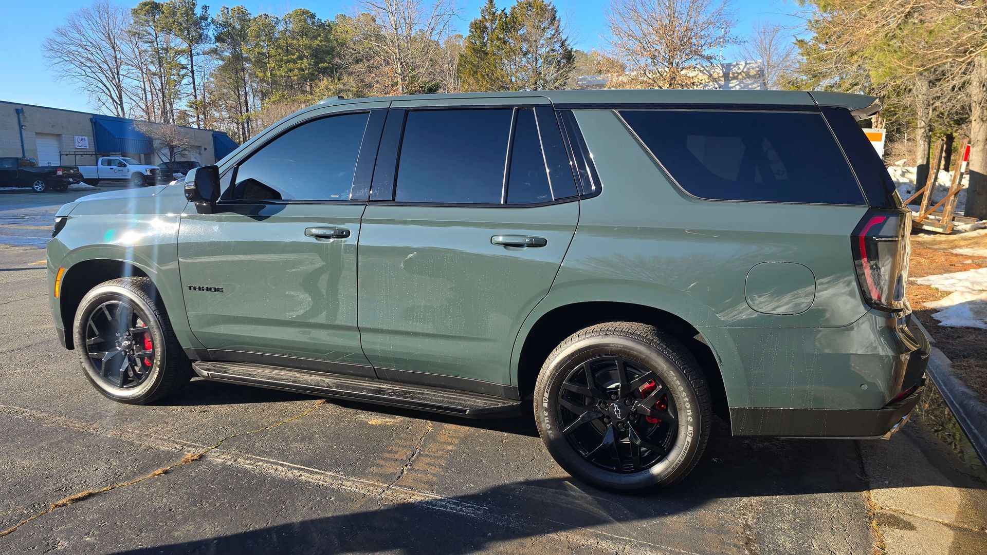 Green SUV parked outdoors on a sunny day, side view with black rims and tinted windows