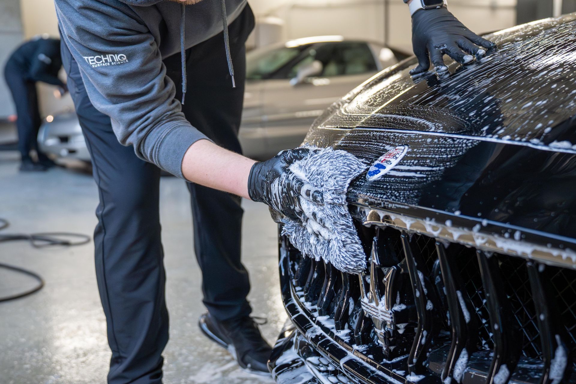 A man is washing a black car with a glove .