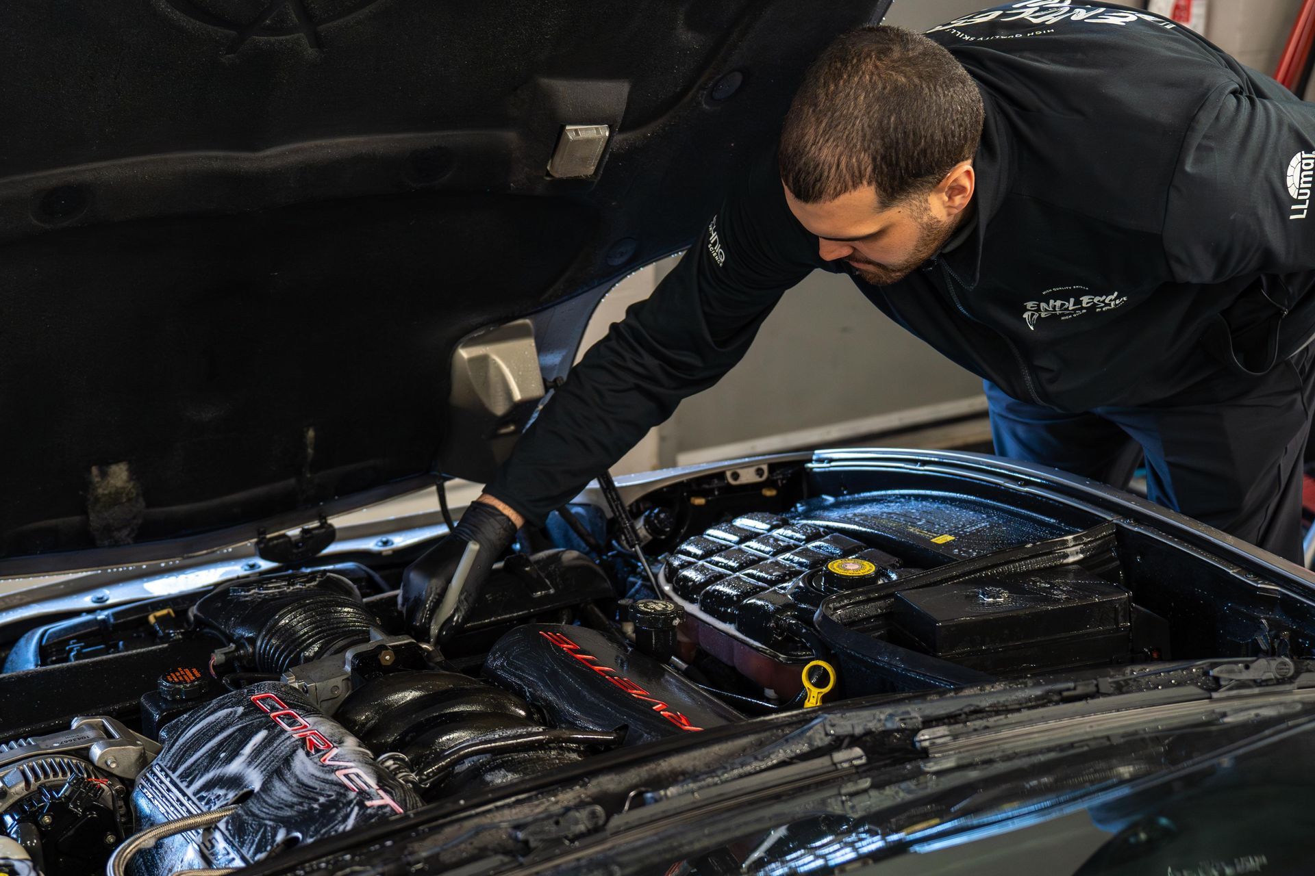 A man is working on the engine of a car with the hood open .
