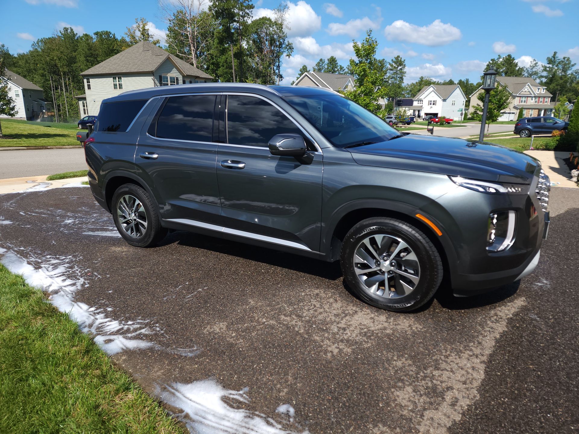 A gray suv is parked on the side of the road in a driveway .