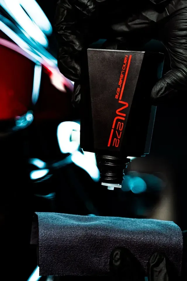 A gloved hand dispenses a liquid from a black
