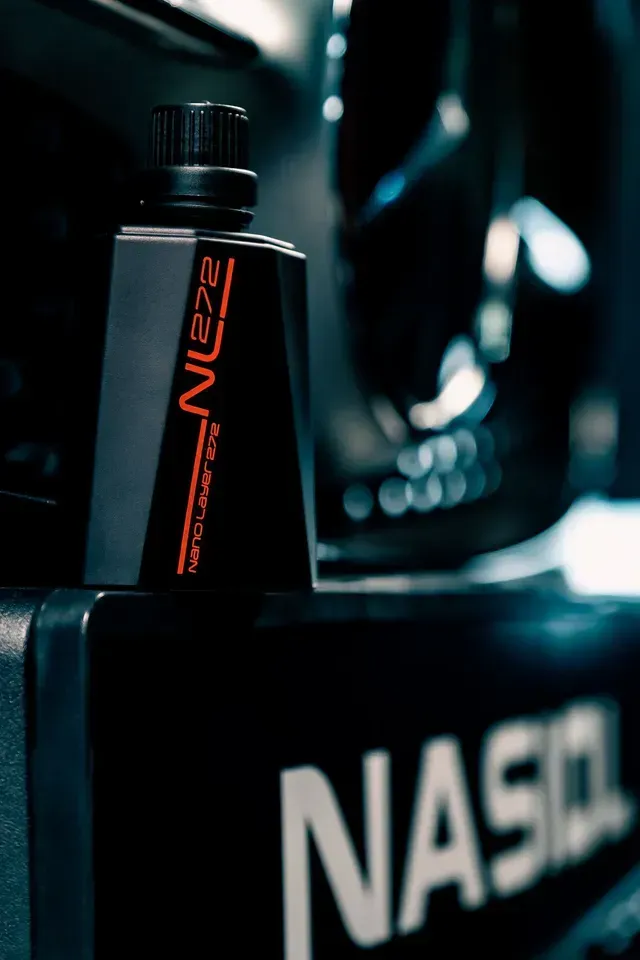 A black Nasiol NL272 nano coating bottle stands on a dark, reflective surface with the brand logo visible below.