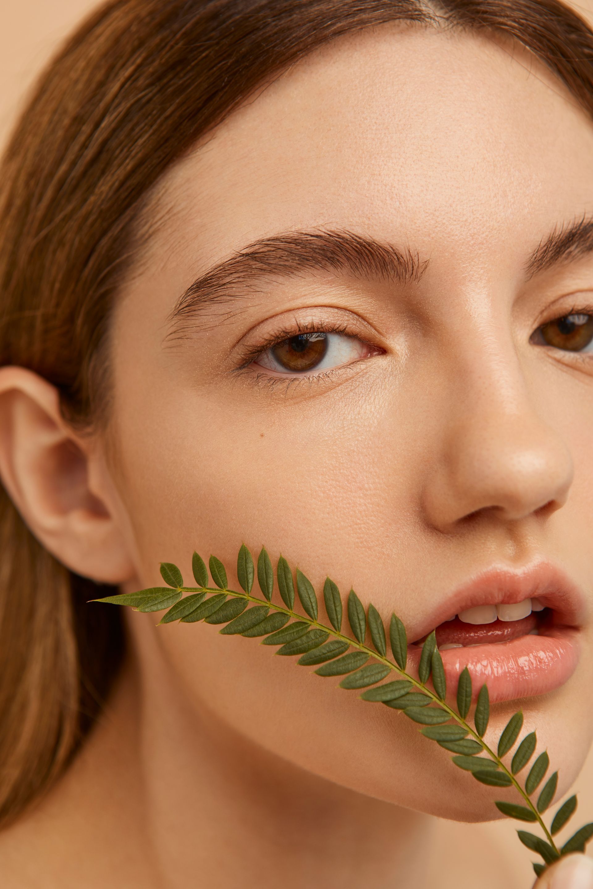 A woman is holding a green leaf in her mouth.
