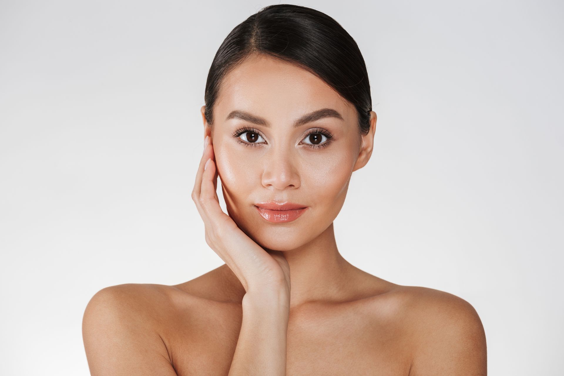 A woman is touching her face with her hand and smiling.