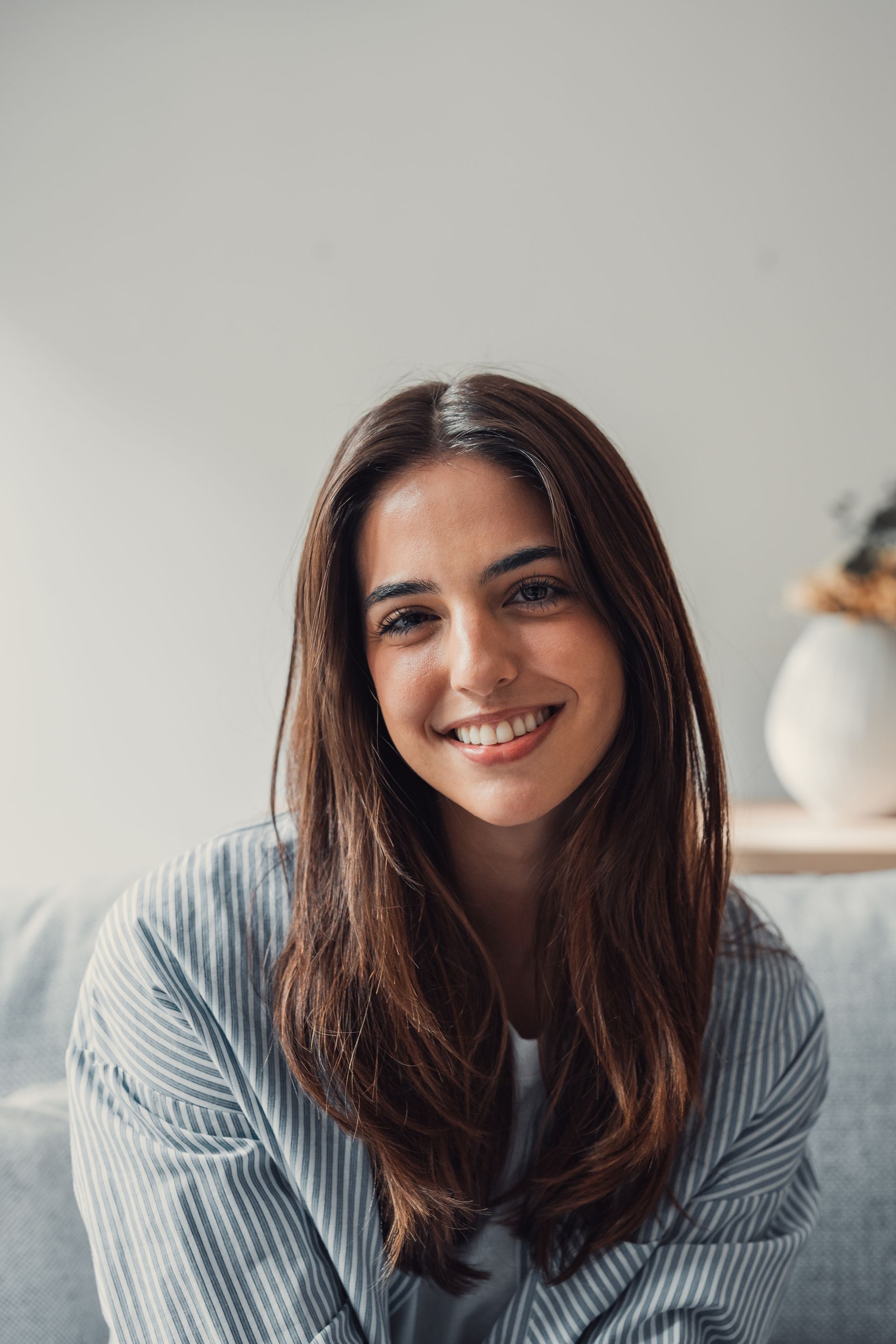 A woman is smiling while sitting on a couch.