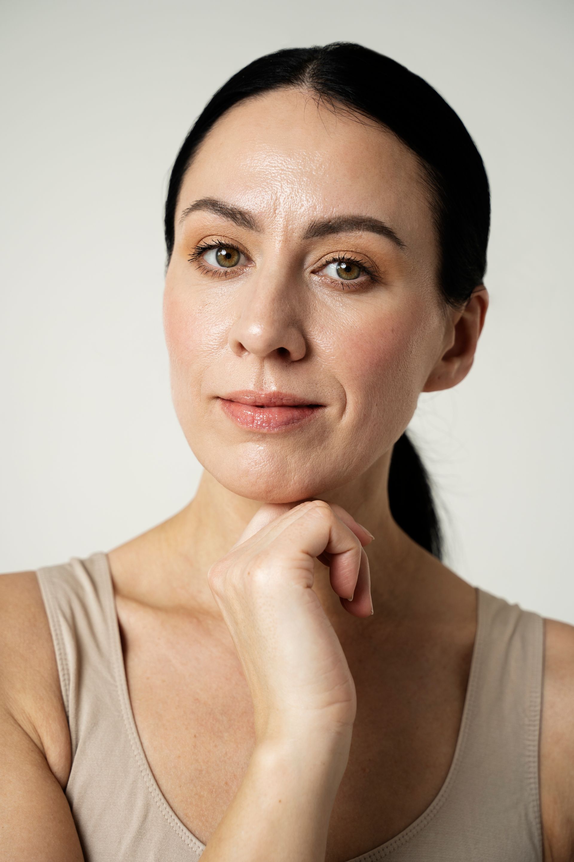 A woman with a hand on her chin is looking at the camera.