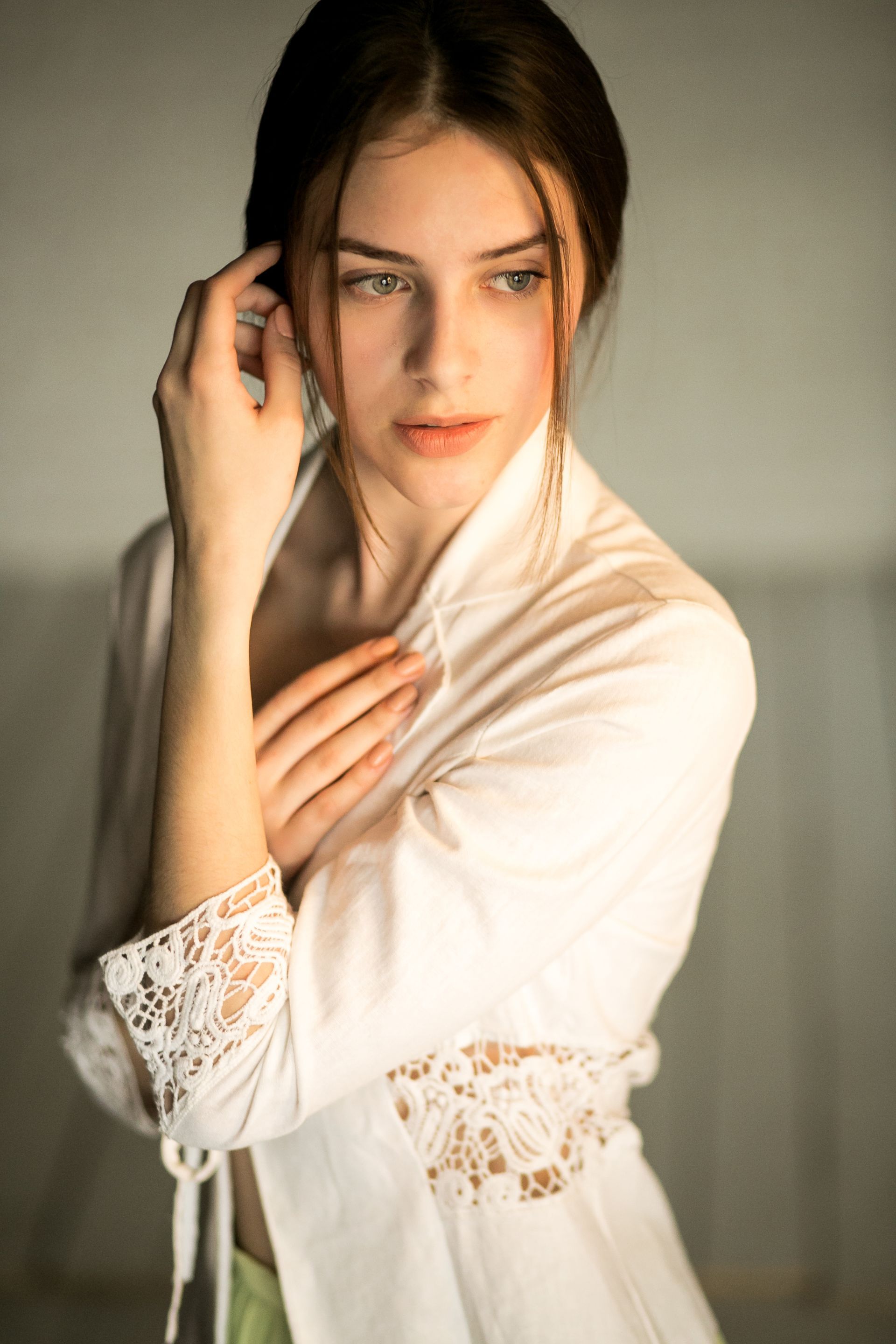 A woman in a white robe is touching her ear with her hand.