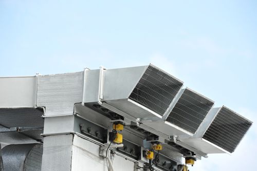 Metal air conditioning vents against a blue sky.