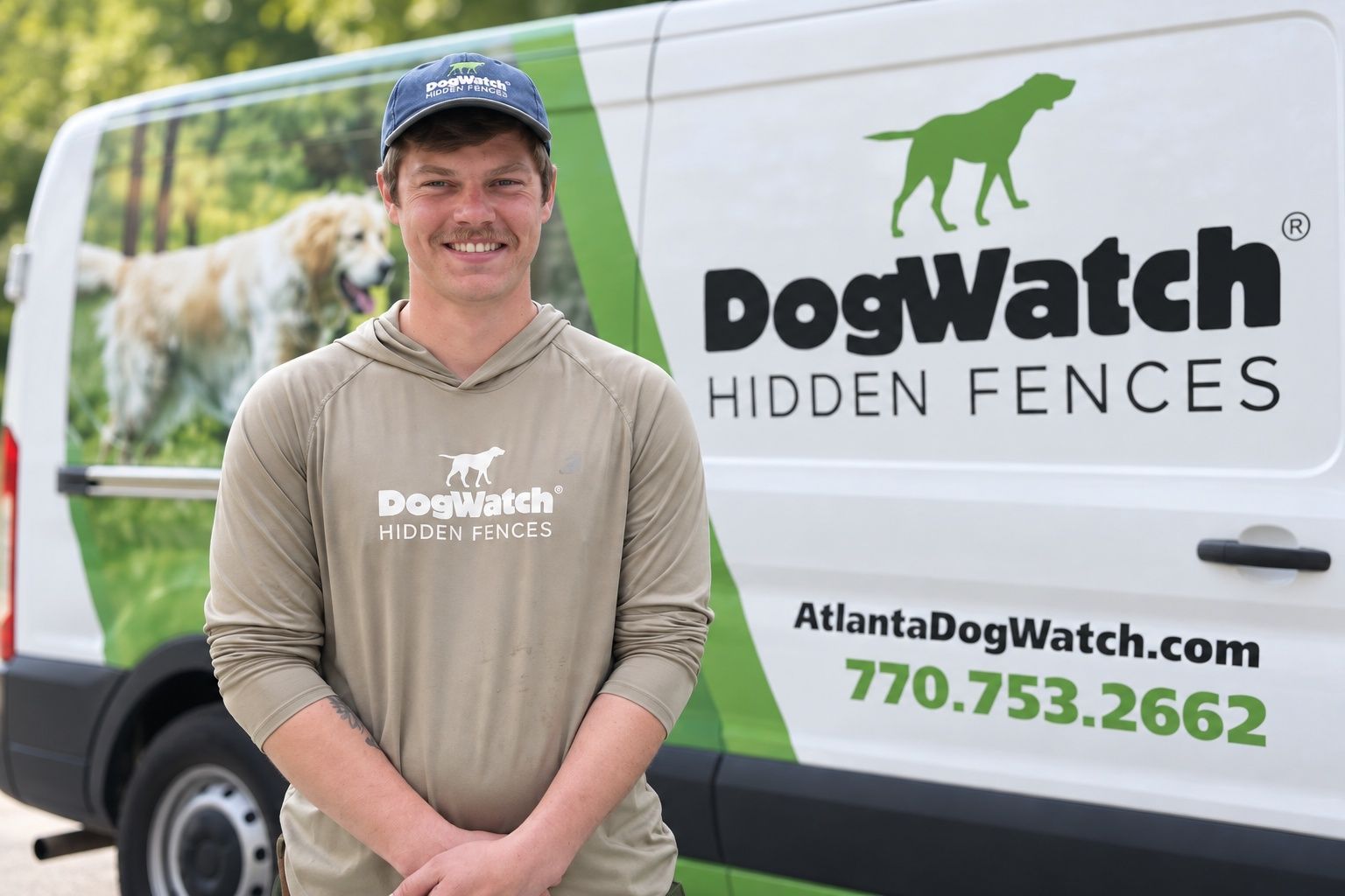 Man in green hoodie and grey vest stands near a DogWatch vehicle with a dog image.