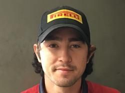 Person wearing a black Pirelli cap and red jacket, looking at the camera with a neutral expression.