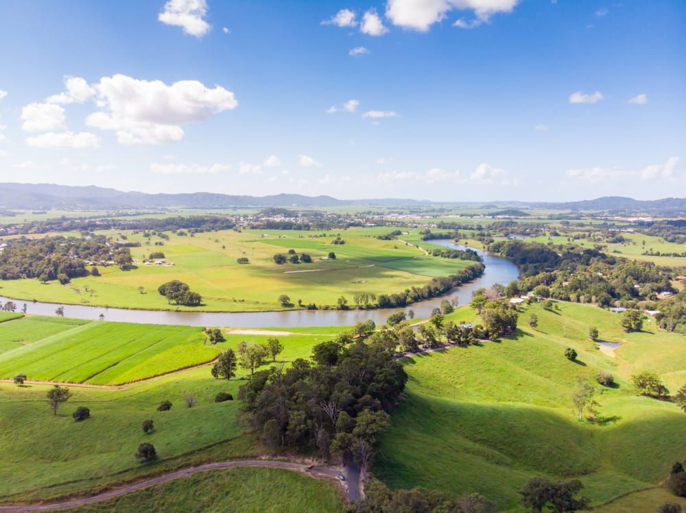 An Aerial View of A River Surrounded by Green Fields and Trees — Lismore Floor Sanding in Murwillumbah, NSW