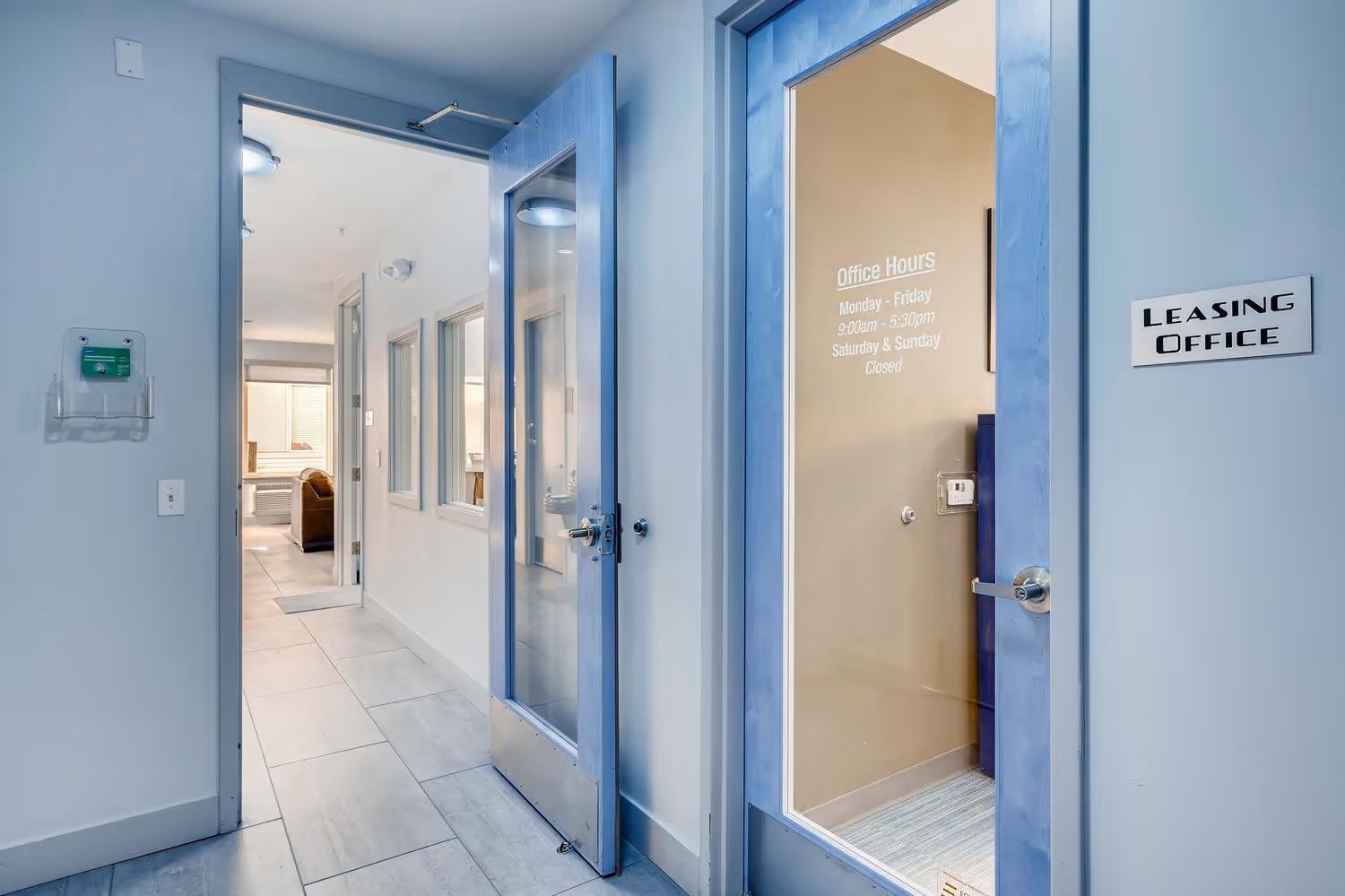 A hallway with blue-framed glass doors, including one labeled 