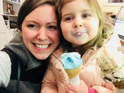 Two smiling people holding ice cream cones, with blue ice cream on one cone and a cozy indoor background.