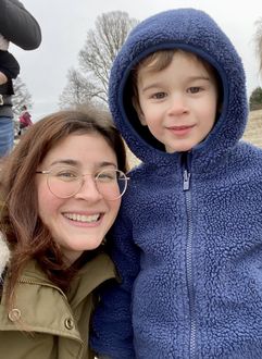 Smiling woman and child bundled in blue winter coats outdoors in snowy weather