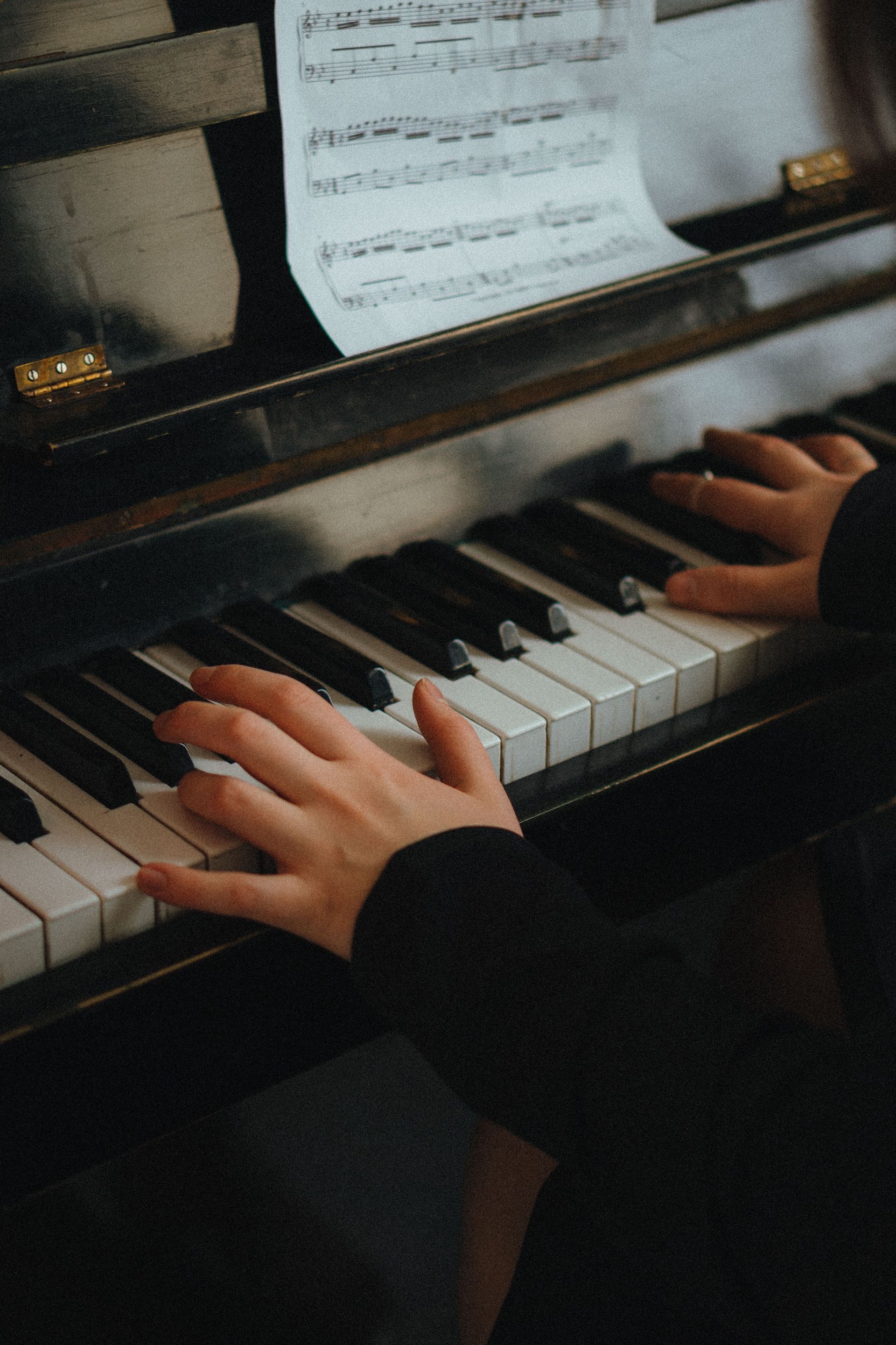 Hands playing a piano keyboard, close-up on black and white keys