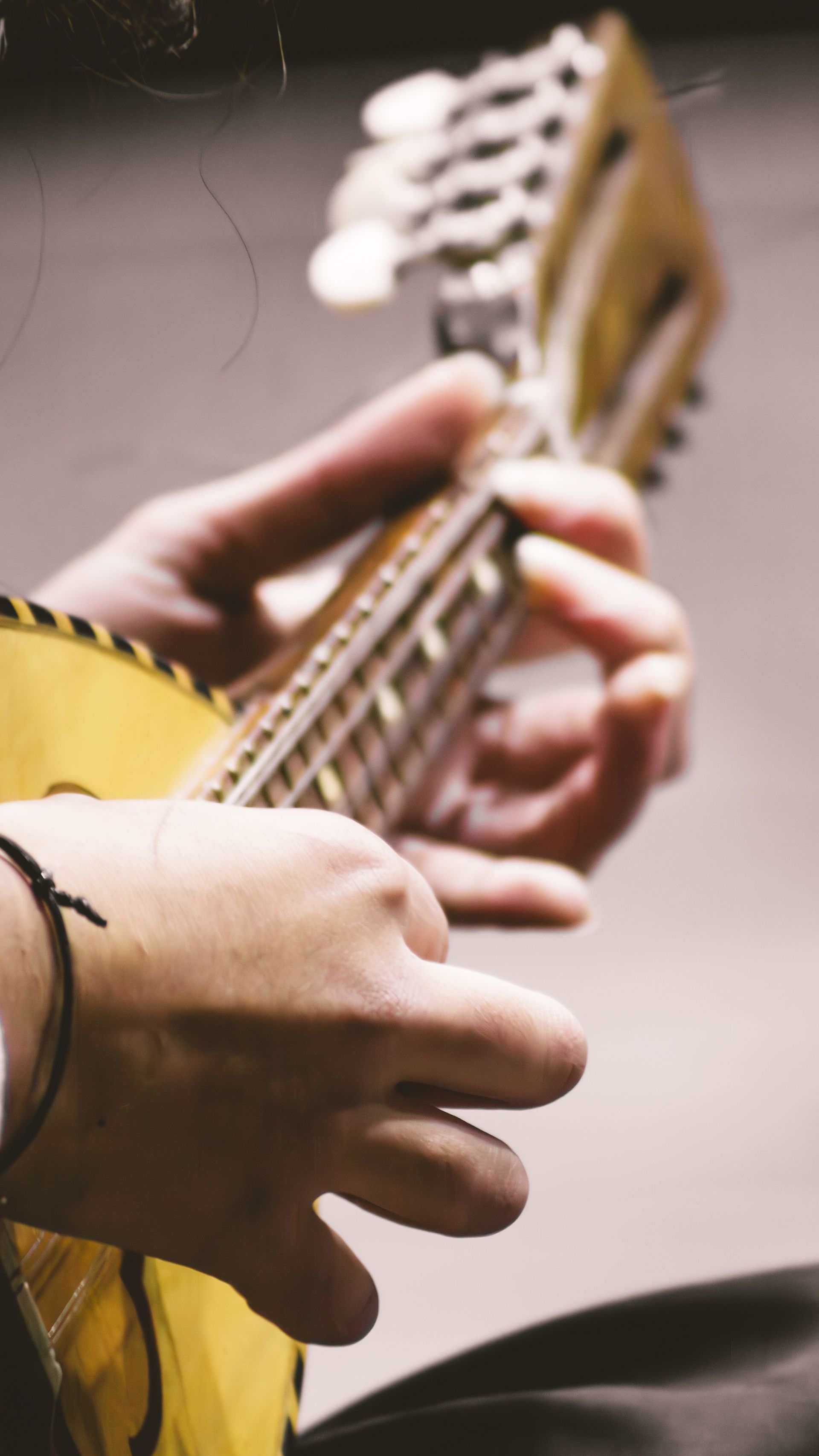 Close-up of a hand playing a banjo, with the white drumhead and fretboard visible.