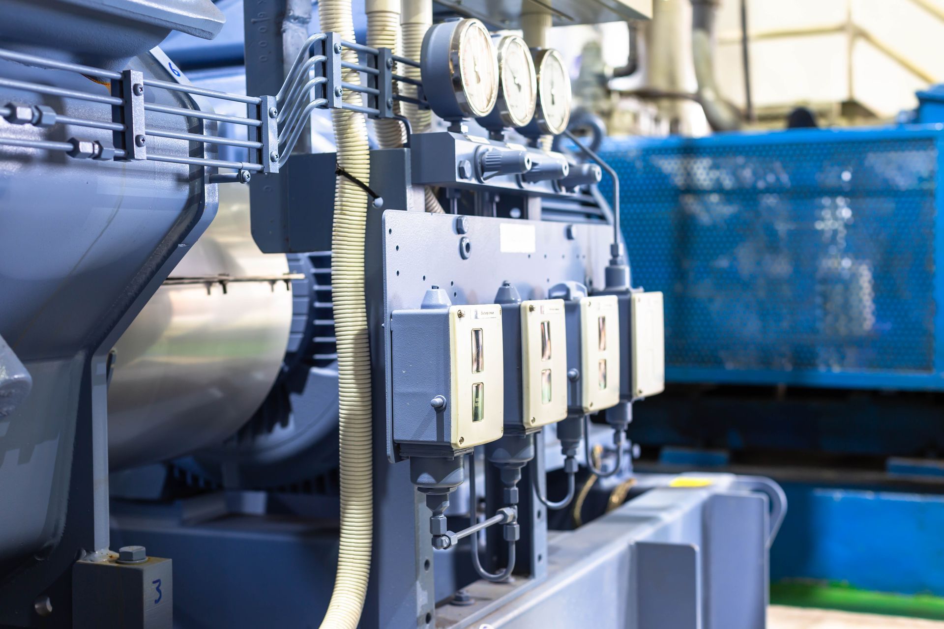 Industrial machinery with control boxes and blue piping in a factory setting