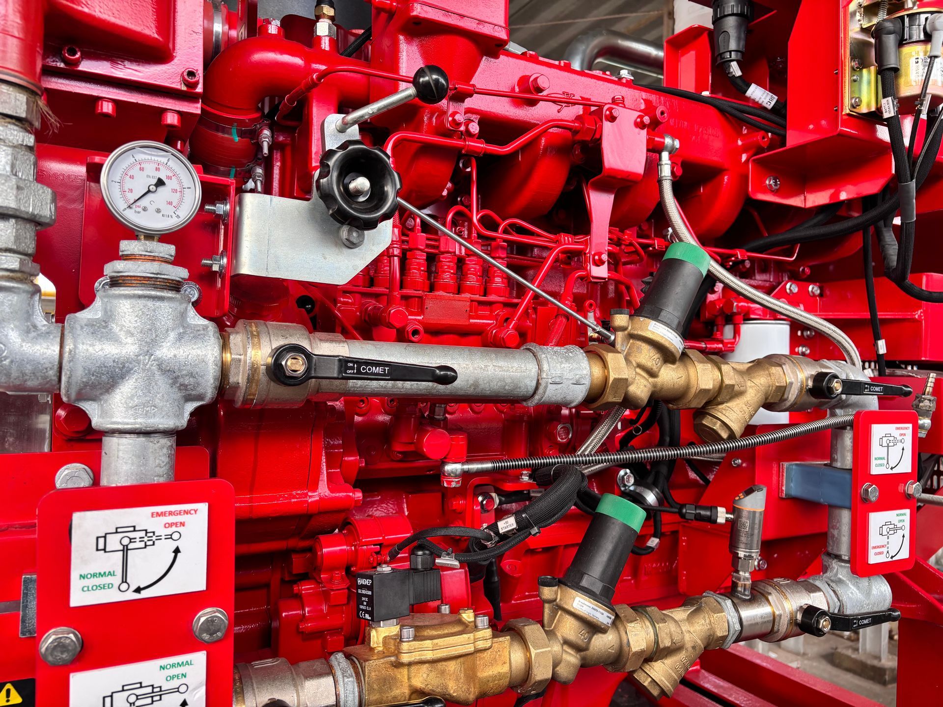 Red industrial fire sprinkler piping with gauges, valves, and bright red control components.