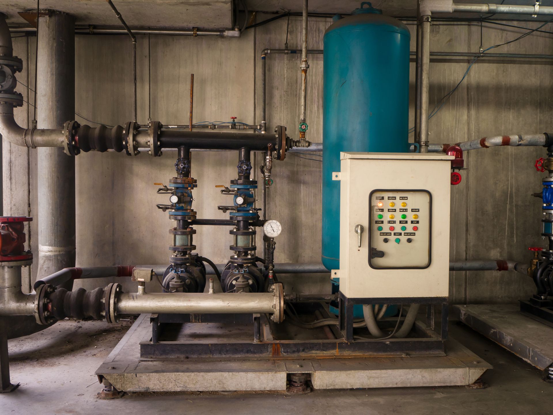 Industrial water treatment system with blue tank, pipes, and control panel in a utility room