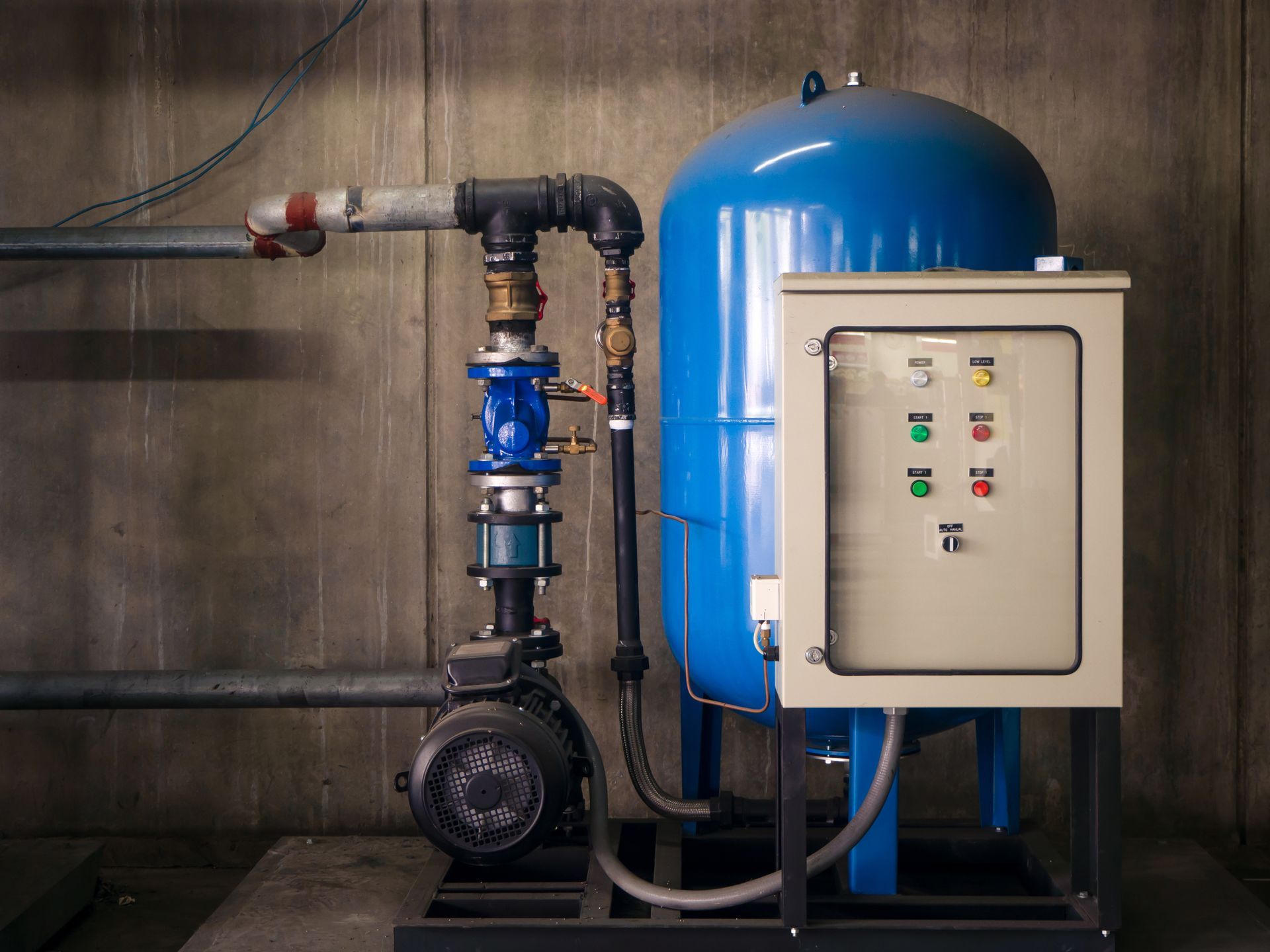 Industrial pump system with blue pressure tank and control panel in a utility room