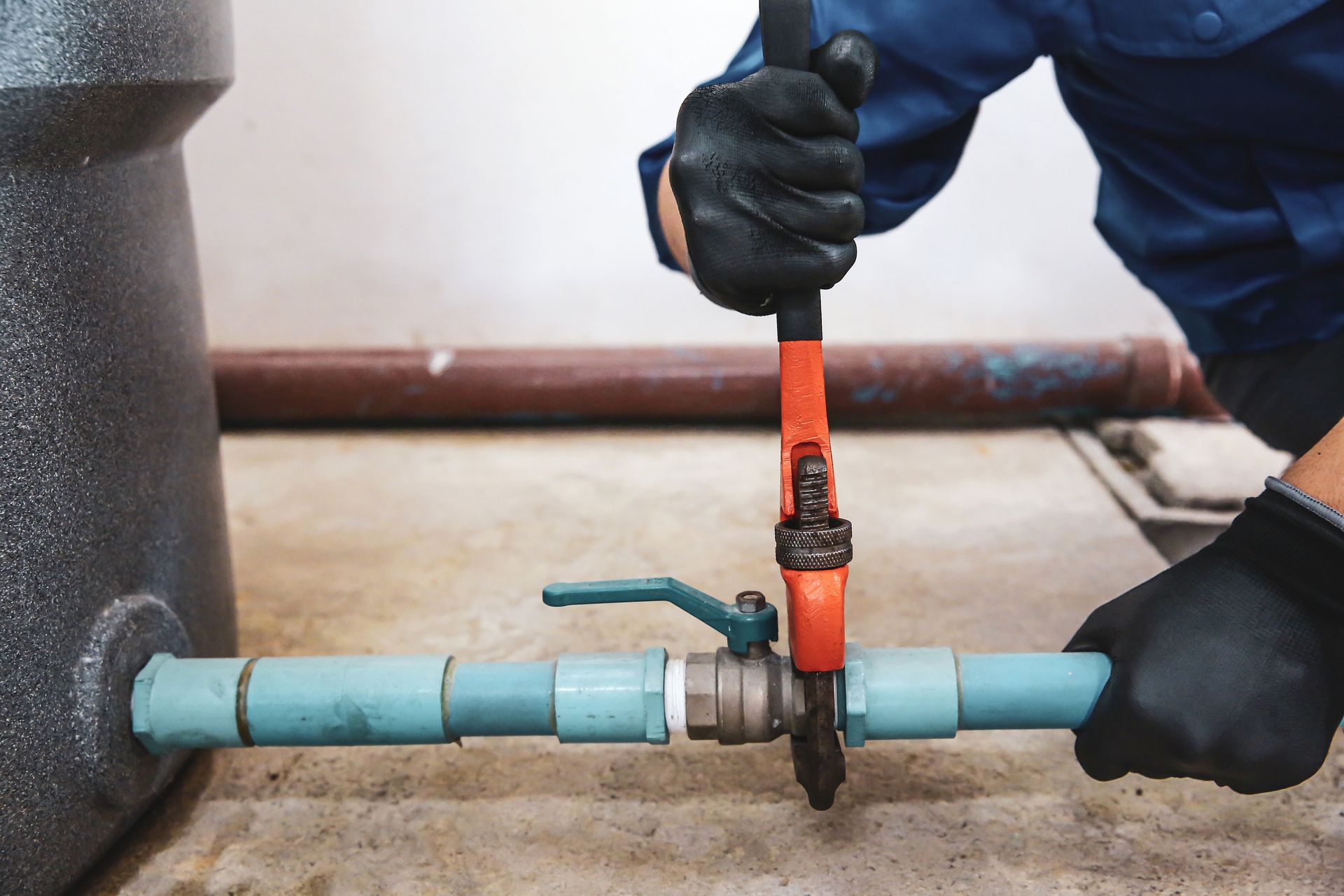 A close-up of a technician using a wrench to repair a water pump pipe.