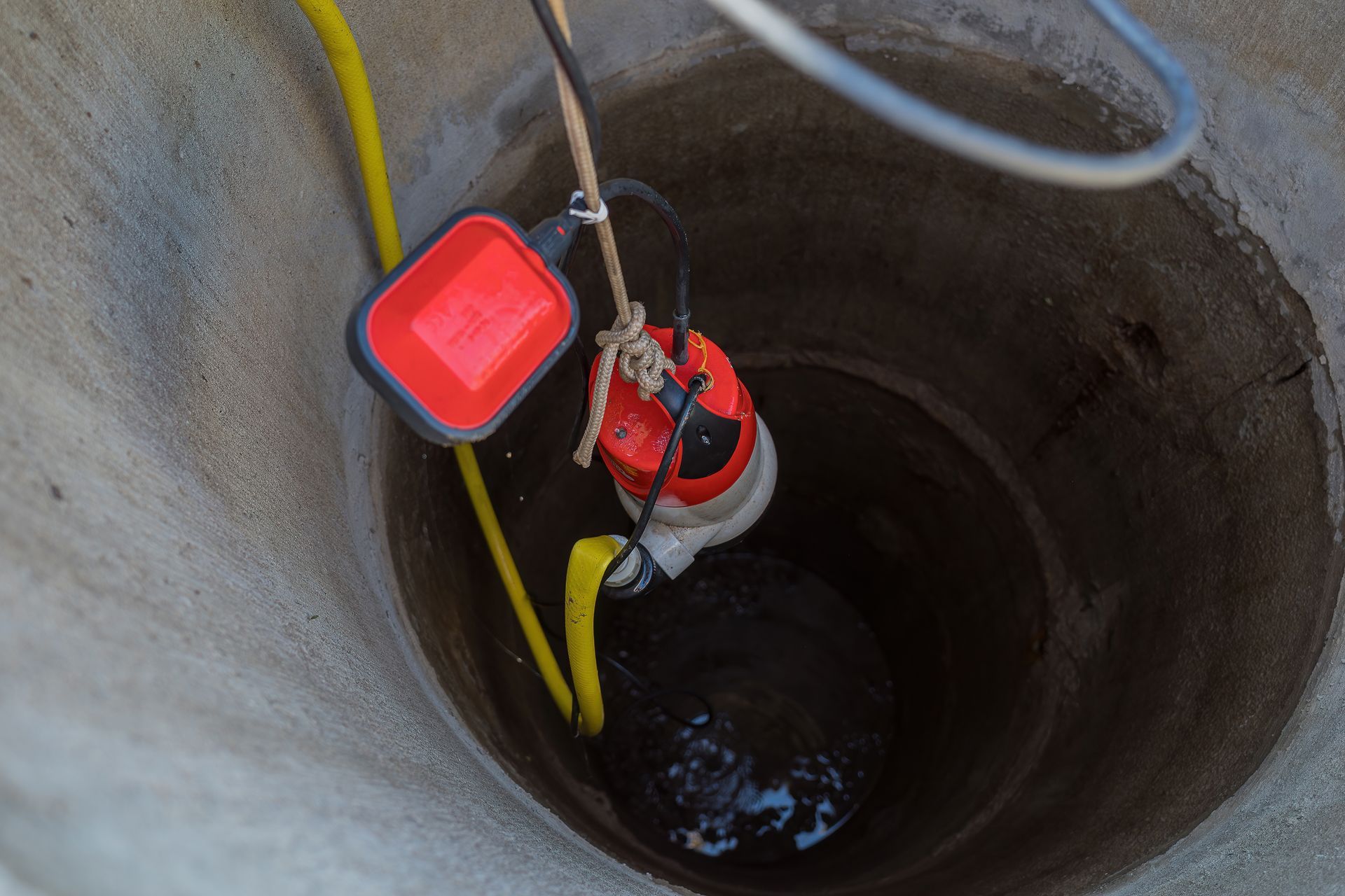 A red and yellow hose connected to a metal pipe, indicating a water or gas supply system.