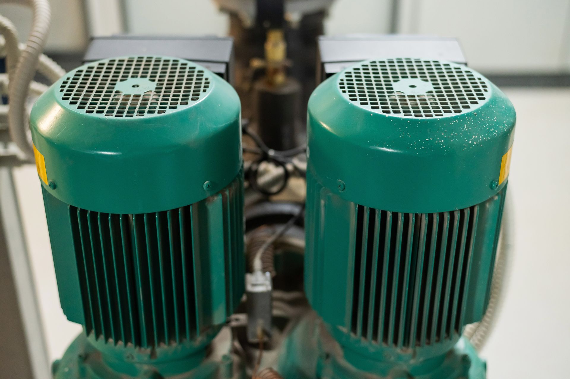 Two green industrial electric motors with vented tops and black cooling fins side by side
