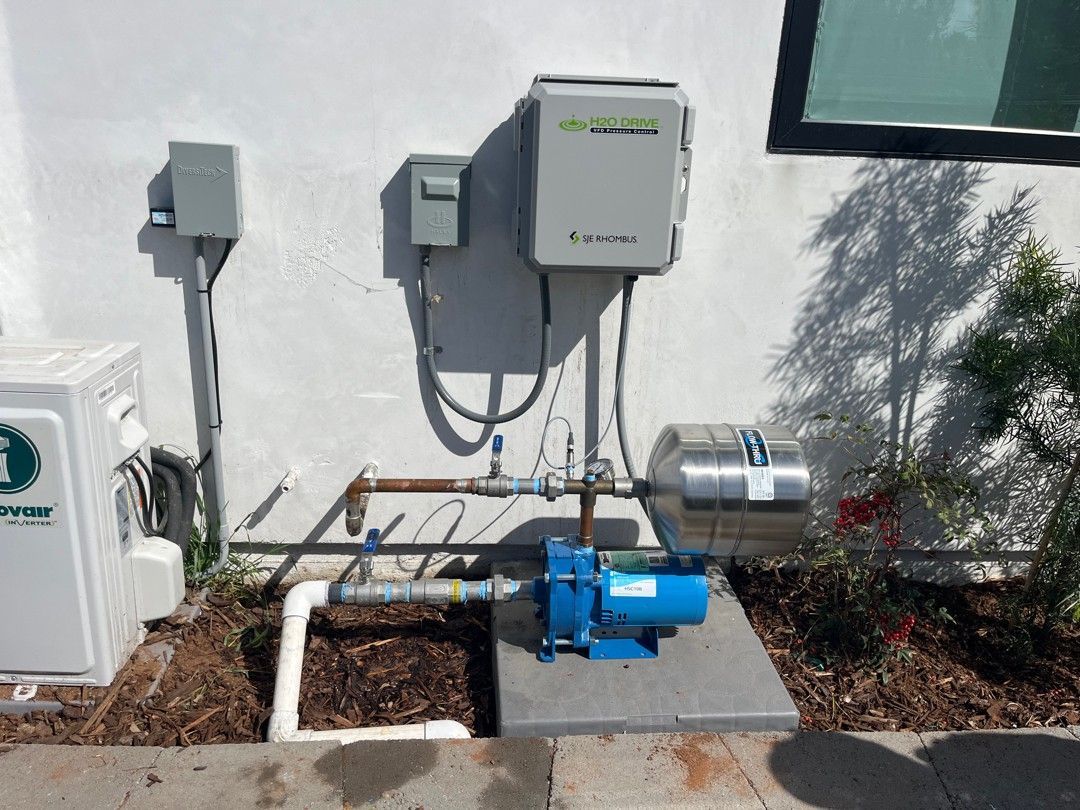 Industrial pipes and a blue valve behind a chain-link fence in an outdoor utility area