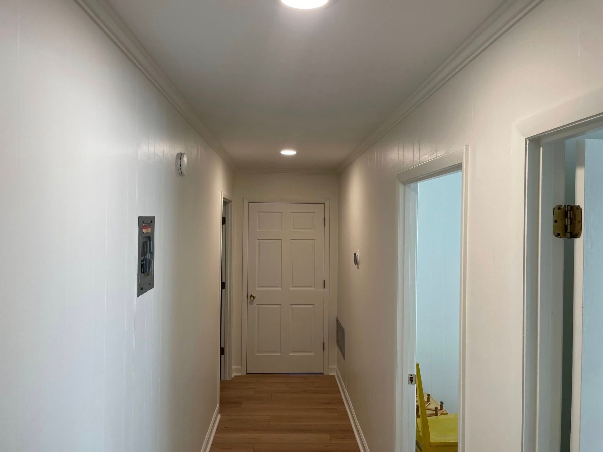 A long hallway with white walls and wooden floors in a house.