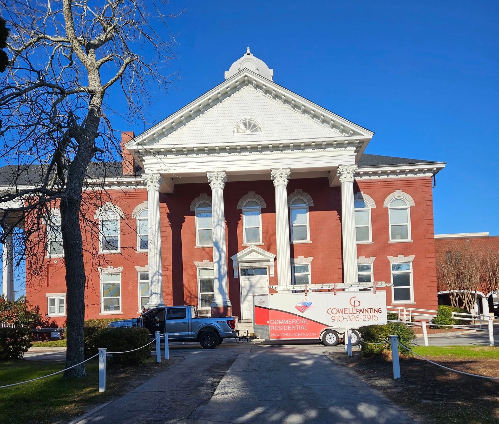 A large red brick building with columns and a truck parked in front of it