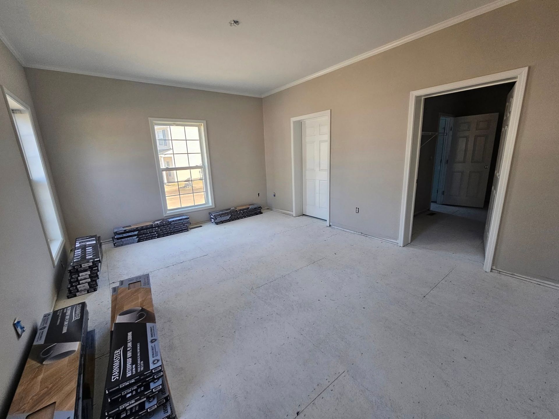 An empty room with a carpeted floor and a window.