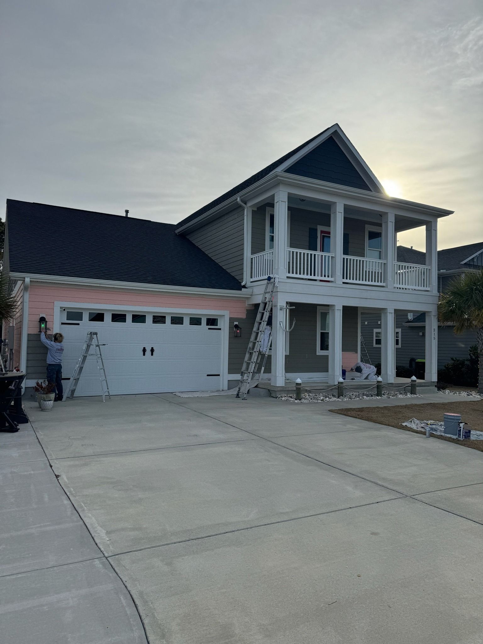 A large house with a blue roof is being painted.