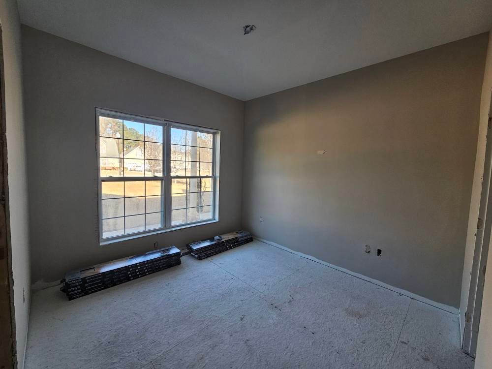 An empty room with a carpeted floor and two windows.