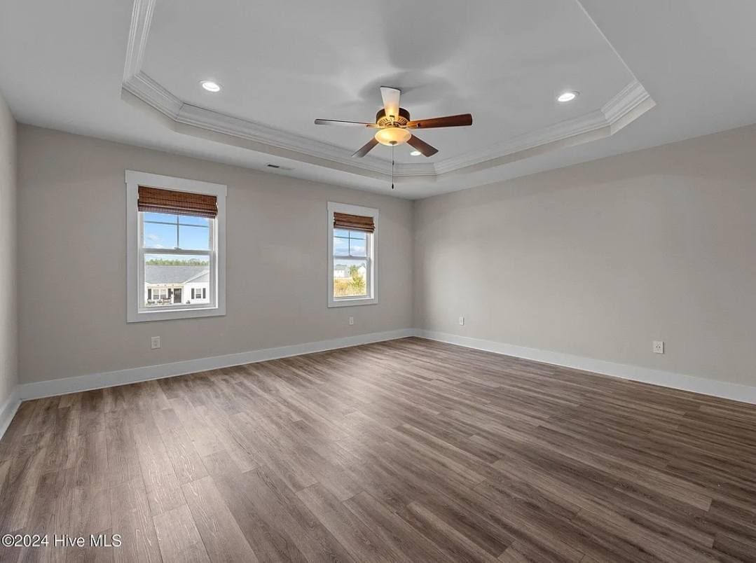 A large empty room with hardwood floors and a ceiling fan.